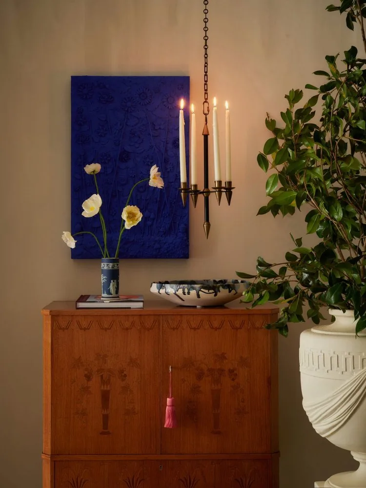 White poppies in a Wedgwood vase top the Swedish inlaid cabinet beside a cobalt blue artwork