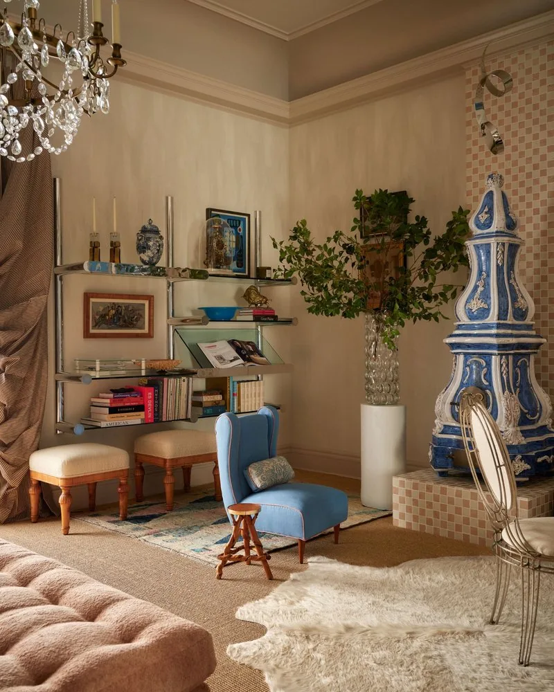 A blue Danish wing chair faces the steel shelving across from the kachelofen in the library corner