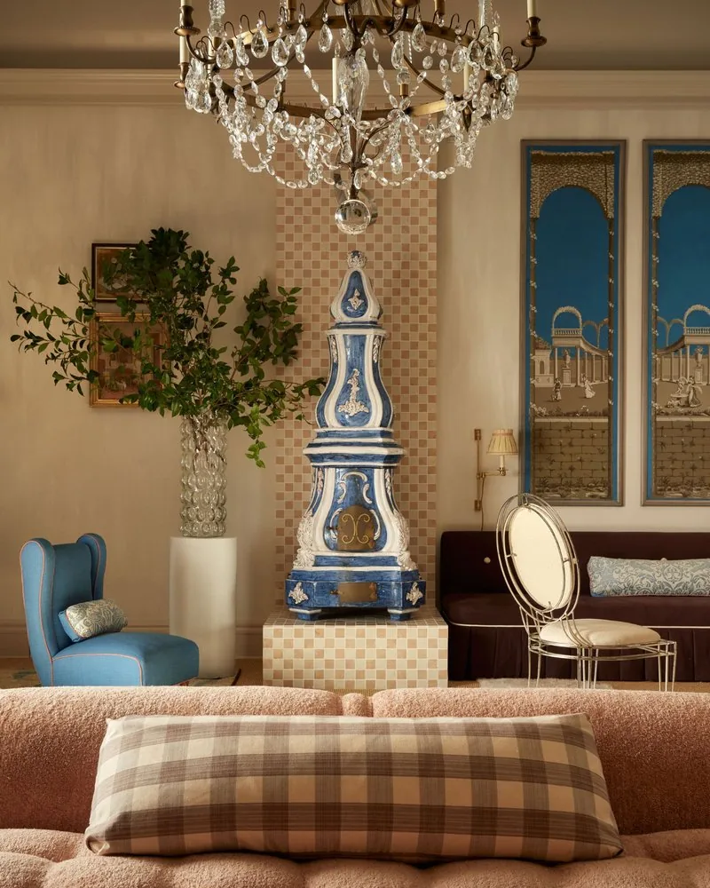 The French majolica kachelofen stands full height on its tiled plinth beneath the crystal chandelier
