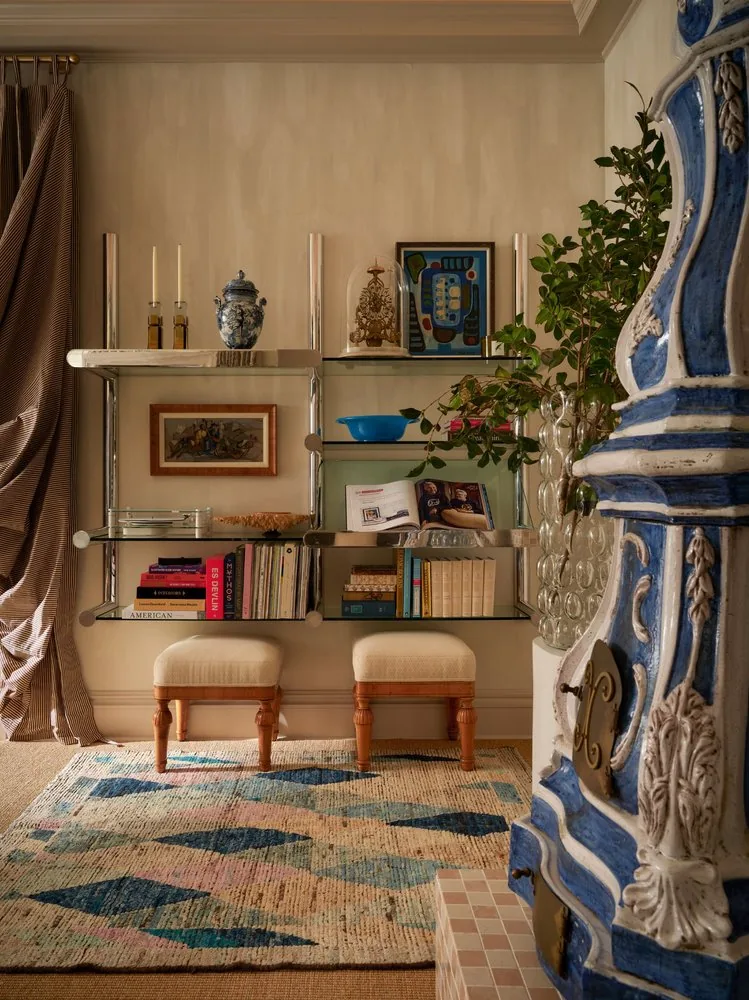 Steel and glass shelving holds art books, Delft ceramics, and framed artwork in the drawing room