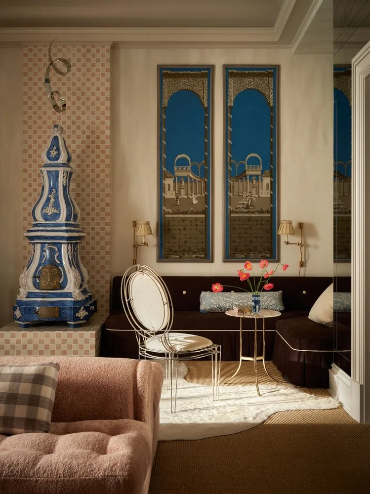 The French majolica kachelofen rises beside Zuber panels and the chocolate velvet daybed